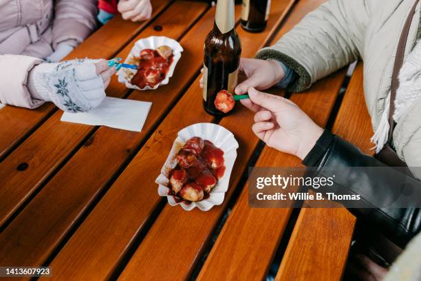 close up of friends eating currywurst and drinking beer - currywurst stock-fotos und bilder