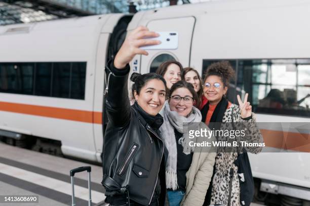 friends taking selfie in front of train together - travel stock-fotos und bilder