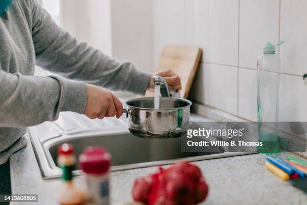 woman filling pan with water - encher - fotografias e filmes do acervo