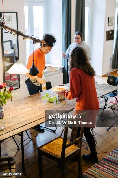 three friends setting up for some food at dining table - rust germany stock-fotos und bilder