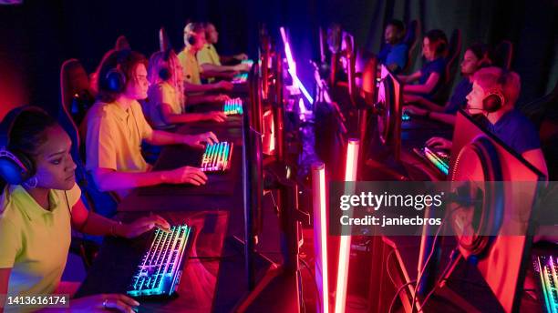 diverse yellow pro gamer female team with african ethnicity leader competing in video game esport championship. blue team on the other side - compete stock pictures, royalty-free photos & images