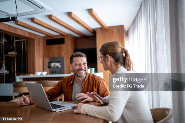 mature couple talking and using the laptop at home - verloren generatie stockfoto's en -beelden