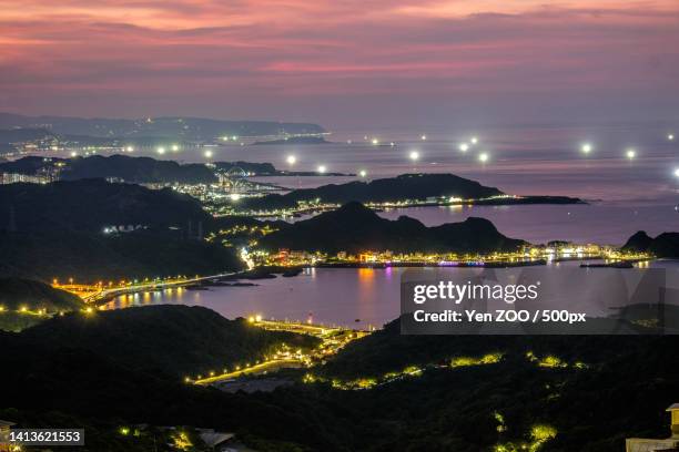 high angle view of illuminated city by sea against sky at sunset - sunset zoo stock pictures, royalty-free photos & images