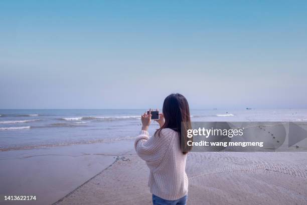 a young asian woman photographing the sea by the sea - samsung galaxy camera stock pictures, royalty-free photos & images