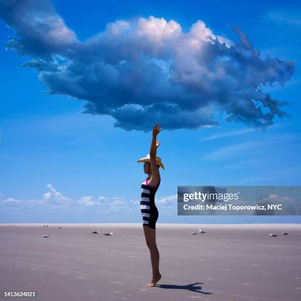 woman standing under dark cloud on the beach - dragon quest stock pictures, royalty-free photos & images