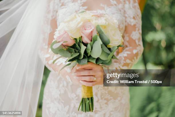 midsection of bride holding bouquet - wedding dress fotografías e imágenes de stock