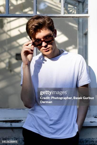 young man with sunglasses - holding sunglasses stockfoto's en -beelden