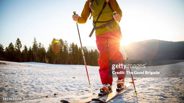 low angle shot of woman skiing with mountains in the background at sunset - calças para esquiar imagens e fotografias de stock
