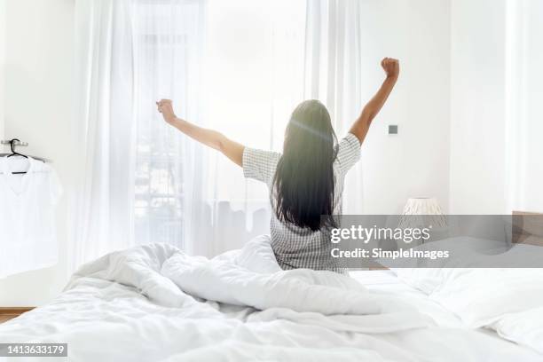 freshly woken up young woman enjoying the morning sun rays. - beds stock pictures, royalty-free photos & images