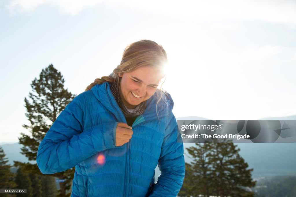 Woman laughing while zipping up ski jacket