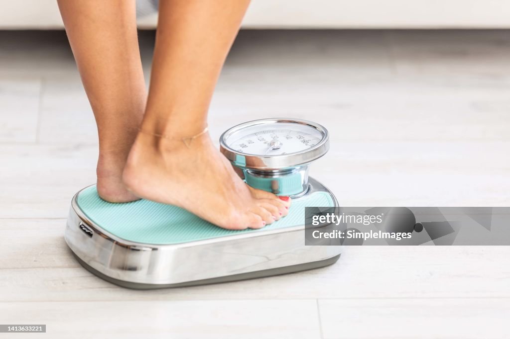 Woman standing on scale, close-up of legs.