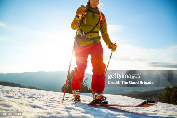 low angle view of young woman skiing against blue sky - pantaloni da sci foto e immagini stock