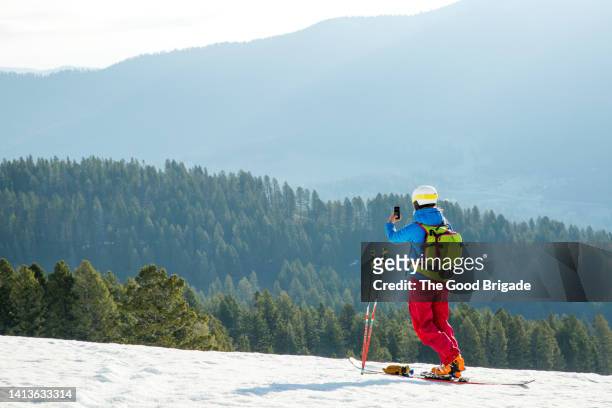 female skiier photographing winter landscape with smartphone - calças para esquiar imagens e fotografias de stock