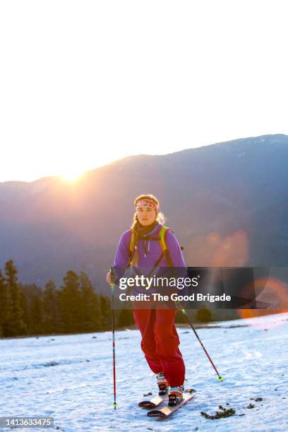 portrait of female skier standing on mountain at sunset - スキーパンツ ストックフォトと画像