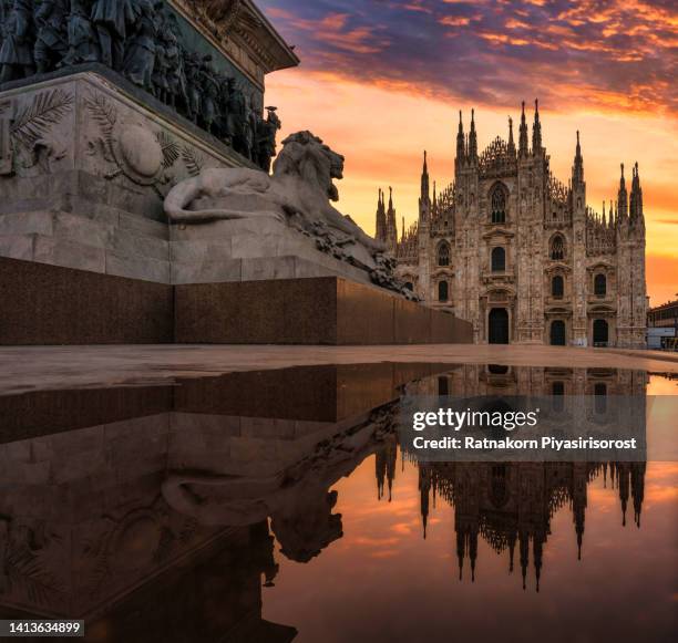 sunrise scene of the ornate gothic facade, soaring spires and magnificent marble towers of the duomo, milan's monumental cathedral under big blue lombardy skies - guglia foto e immagini stock