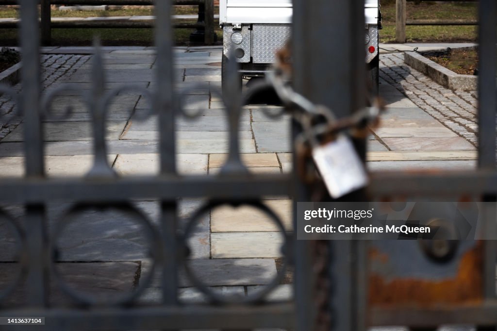 Closed & padlocked iron gate surrounding college campus