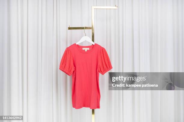 red cotton blouses hanging on rack at home - hanging blouse stock pictures, royalty-free photos & images