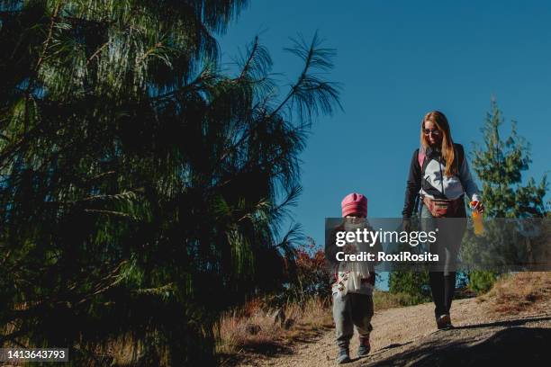 mother and daughter with a lot of coat walking in the forest - cordoba argentina fotografías e imágenes de stock