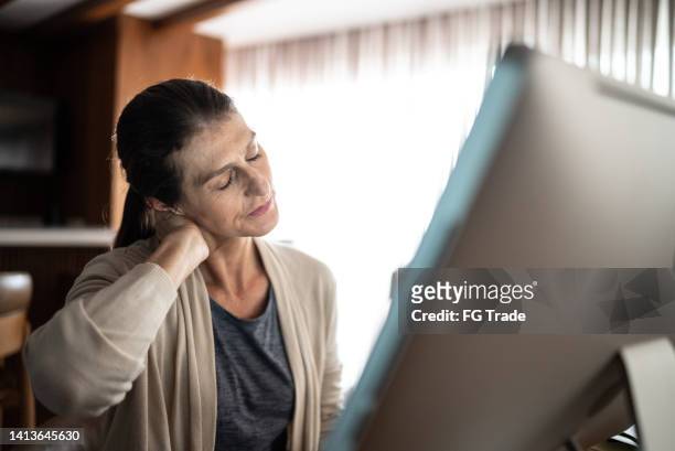 mature woman with neck pain while using the computer at home - herniated disc 個照片及圖片檔