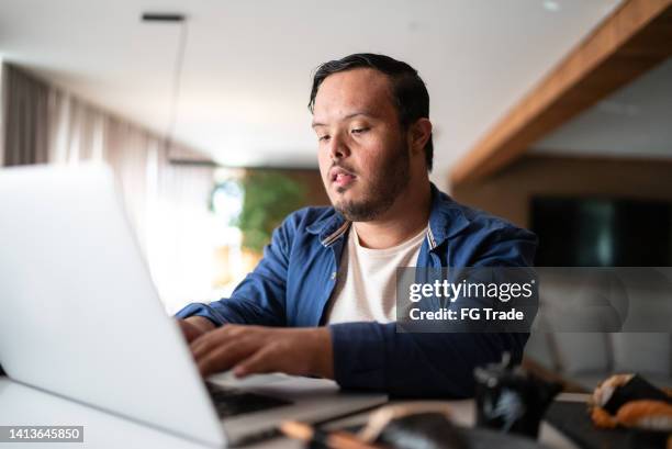 young man with special needs using the laptop at home - disability worker stock pictures, royalty-free photos & images