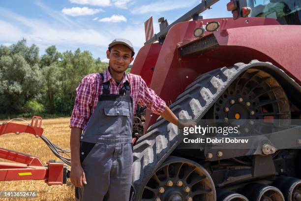ein traktorfahrer lehnt sich an die kette seines traktors. - bartstoppel stock-fotos und bilder