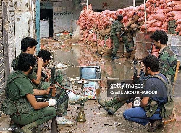 Militiamen from Amal, the first political organization of Lebanon's Shi'ite Muslims, watch 12 June 1986 on a portable TV a Mundial soccer match...