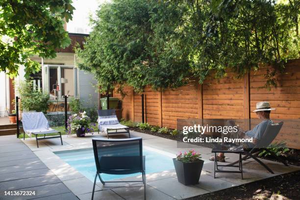 a man reading in his back yard by the pool - garden fence stock pictures, royalty-free photos & images