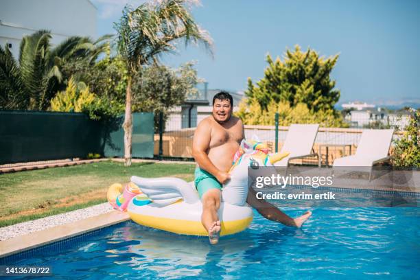 uomo che salta in piscina con unicorno gonfiabile - crazy pool foto e immagini stock