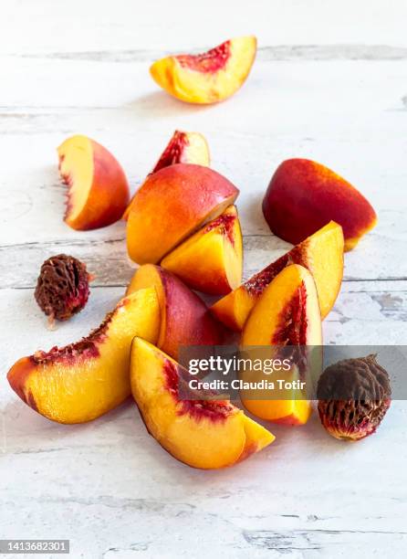 sliced yellow peaches on wooden white background - nectarine stock-fotos und bilder