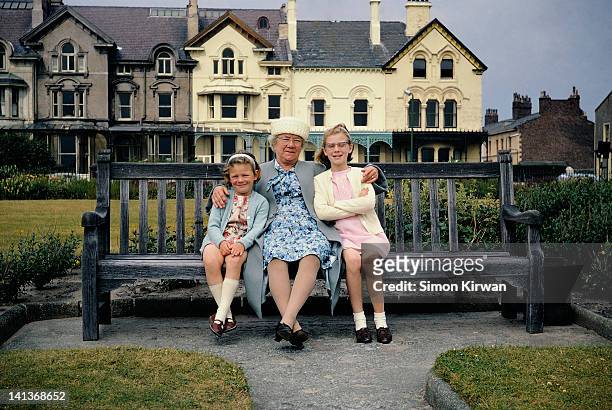 grandmother and grand-daughters on park bench - liverpool england stockfoto's en -beelden