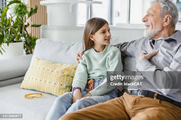 grandfather tells the story to the granddaughter at home - granddaughter stock pictures, royalty-free photos & images