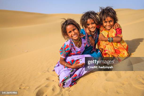 three indian girls playing on a sand dunes near their village, india - rajasthani youth stockfoto's en -beelden