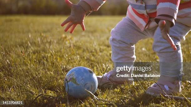 safe the earth. baby plays with globe ball in nature at sunset. - annual legacy stock pictures, royalty-free photos & images