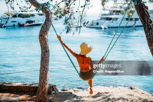 young woman swinging on a swing on the beach - woman on swing stock pictures, royalty-free photos & images