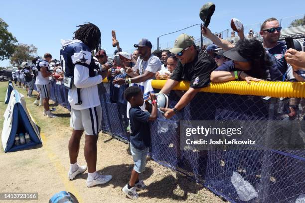 Trevon Diggs of the Dallas Cowboys and son Aaiden sign autographs during training camp at River Ridge Fields on August 08, 2022 in Oxnard, California.