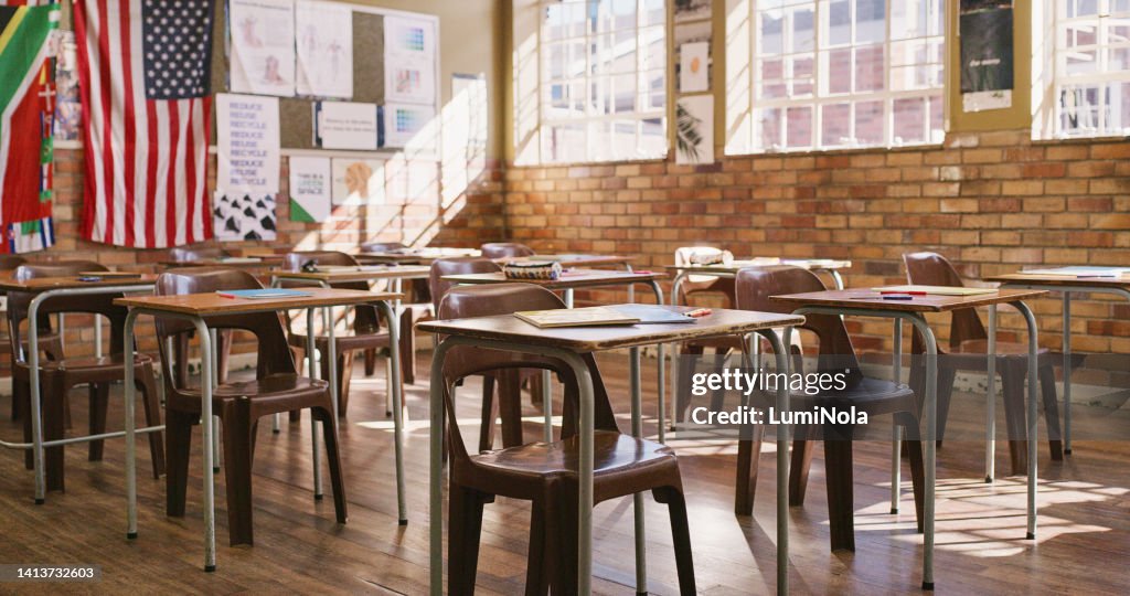 Empty classroom with wooden desks, table and chairs for a lesson inside an elementary, middle or high school. Education, learning and knowledge to study for teaching academic students, kids and youth