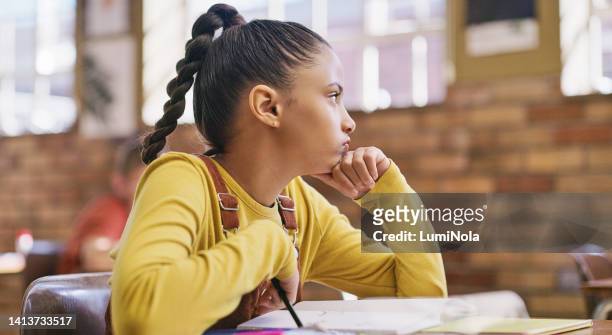 angry, bored and frustrated school student sitting inside a learning classroom with classmates. young girl struggling with writing a homework assignment, test or academic essay in education class - 10 11 jaar stockfoto's en -beelden