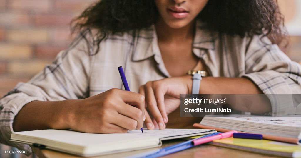 Clever, smart and intelligent female student writing in a book in a classroom in college. Closeup of African woman studying and drafting notes in a notebook inside a class at university