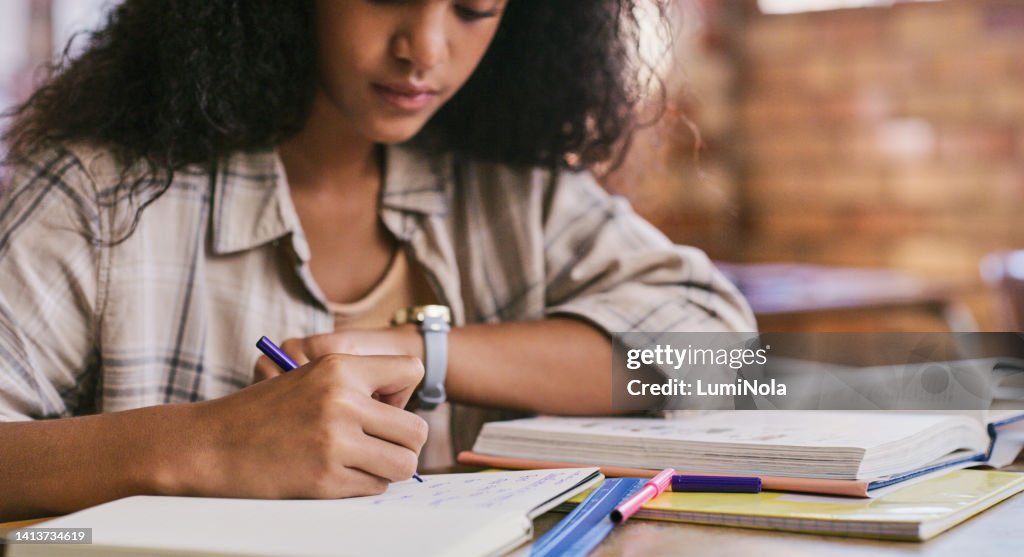 Smart and creative student planning and writing notes in her books at school inside classroom. One young teen girl reading, studying and learning knowledge in an educational class
