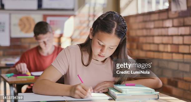 study, classroom and educational learning for children writing essay or exam at school. teenage girl with textbooks and notebook during a test or lesson in class. students serious about education - junior stock pictures, royalty-free photos & images