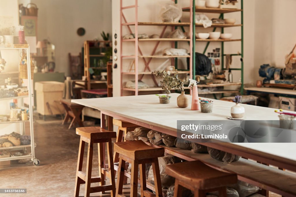 Studio, loja de arte e oficina de cerâmica com mesa de madeira, cadeiras e móveis para confecção de produtos de argila com lama cerâmica. Sala vazia com equipamentos para fazer e projetar artesanato, artístico ou hobby
