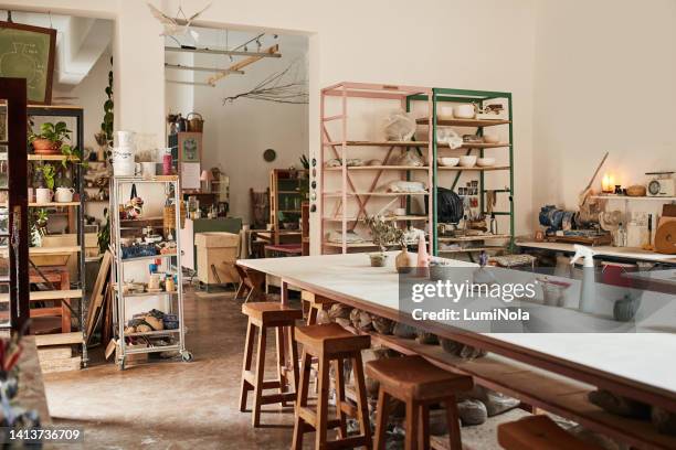 interior of modern pottery studio or creative workshop space filled with shelves and table of hand made fine art and ceramics. clay molding and sculpture class for culture crafts with wood chairs. - trabalho manual imagens e fotografias de stock