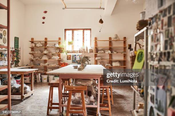 un magasin ou un atelier de poterie en argile vide avec un bureau de potier et une collection d’artisanat fait à la main sur une étagère dans un magasin vide pendant la journée. lieu de travail d’artisan avec pots, assiettes et pots en céramique s - atelier dartisan photos et images de collection