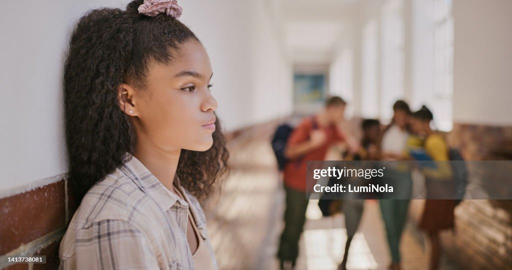 Young sad teenage girl feeling lonely and excluded at school. Female outside classroom and thinking about teen problems, bullying or trouble feeling depressed and anxiety.