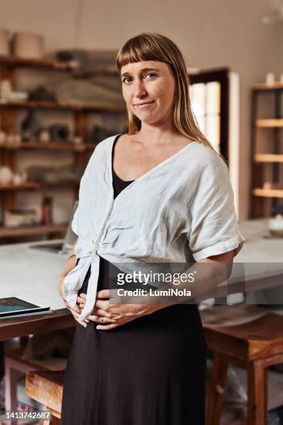 pregnant woman, parent or working mother standing in a workshop and looking happy to be a small business owner. portrait of a young female holding her stomach, feeling positive and confident - bumpy stock pictures, royalty-free photos & images