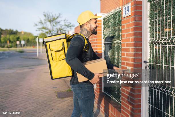 delivery man bringing home a package rings the bell - door bell stock-fotos und bilder