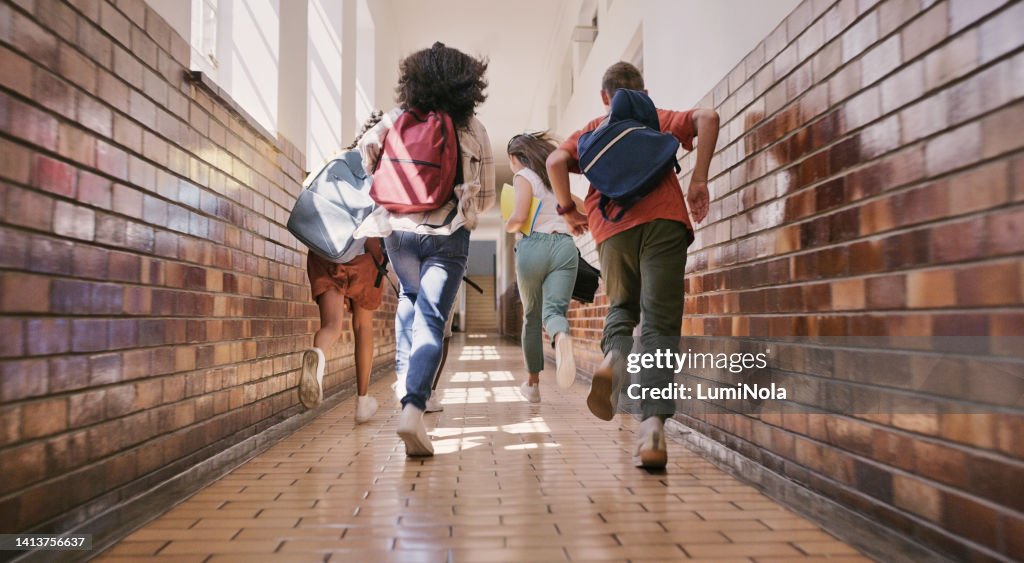 Lustige, glückliche und aufgeregte Schüler, die rennen, rennen und einen Schulflur hinuntereilen, um zu brechen oder zu pausieren. Rückansicht einer Gruppe vielfältiger und verspielter Kinder, die sprinten, um mit ihren Freunden zu spielen