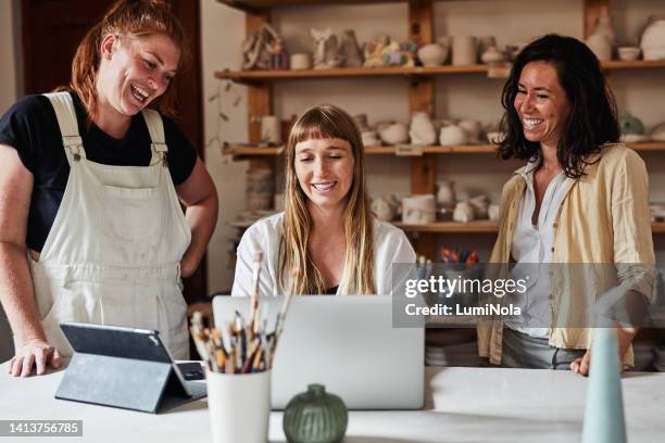 feliz equipo de negocios juntos en la computadora portátil en la tienda de cerámica mirando los pedidos de los clientes. compañeros de trabajo en taller de vajilla admirando su obra de arte digital. pequeña empresa amigable de creativos hechos a mano. - young artists unite fotografías e imágenes de stock