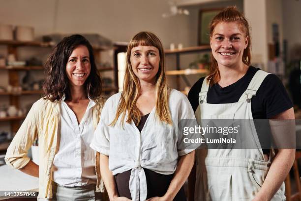 creative designer, artist and design professional standing together as a team in a modern art workshop or ceramic gallery. young female entrepreneur colleagues looking confident and smiling in store - young artists unite stock pictures, royalty-free photos & images