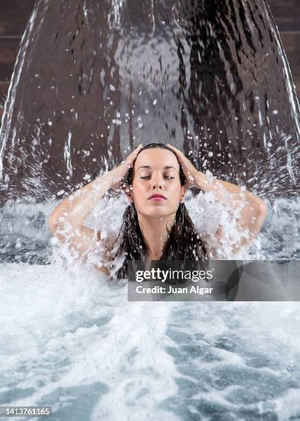 feminine lady touching hair under waterfall in swimming pool - algar waterfall spain stock pictures, royalty-free photos & images